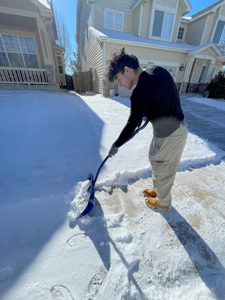 Person shoveling snow from a residential driveway on a winter day
